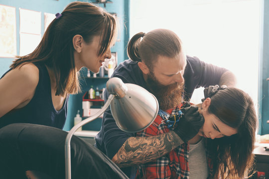 Professional tattoo artist teaching trainee in salon. Apprenticeship concept