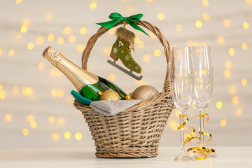 Bottle of champagne with Christmas balls in wicker basket and glasses on table