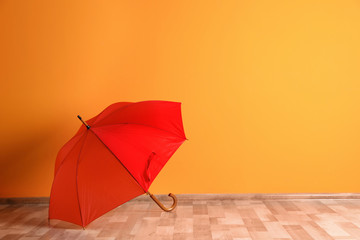 Beautiful open umbrella on floor near color wall with space for design