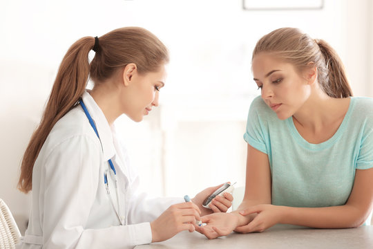 Doctor Using Lancet Pen And Digital Glucometer To Check Diabetic Patient's Blood Sugar Level In Hospital