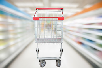 Supermarket aisle blur defocused background with empty red shopping cart