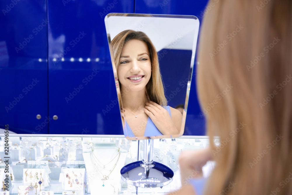 Wall mural young woman trying on necklace in jewelry store