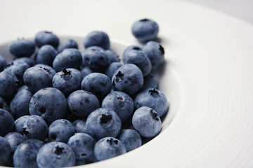 Juicy and fresh blueberries in white plate, closeup