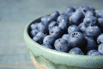 Crockery with juicy and fresh blueberries on wooden table, closeup
