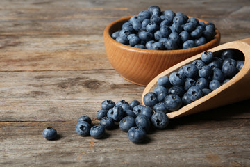 Dishware with juicy and fresh blueberries on wooden table