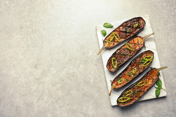 Board with fried eggplant slices on grey background, top view. Space for text