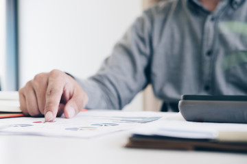 Businessman analyzing investment data charts by using his laptop and calculator in modern office, Business and Office concept.