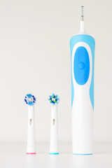 Modern electric toothbrush and spare heads on white background