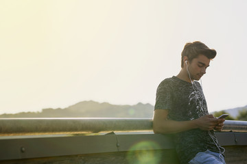 Boy looking at mobile phone at  Bridge