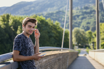 The young man with earphones is using mobile phone