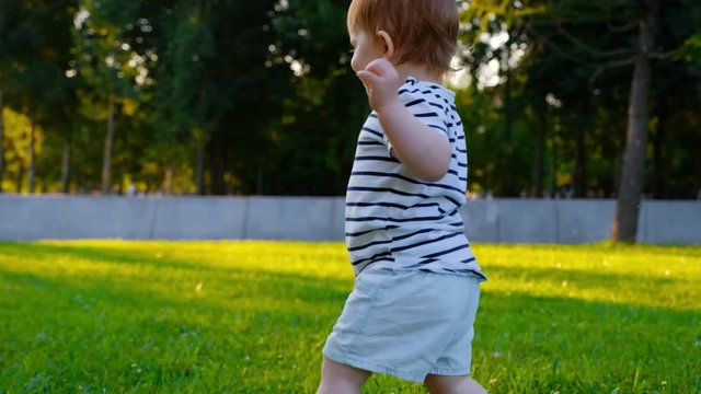 Cute Little baby girl runs by grass at sunset in a park in suumer day. 4k. Happy childhood. Family