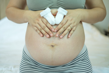 Small sock for the unborn baby in the belly of pregnant woman