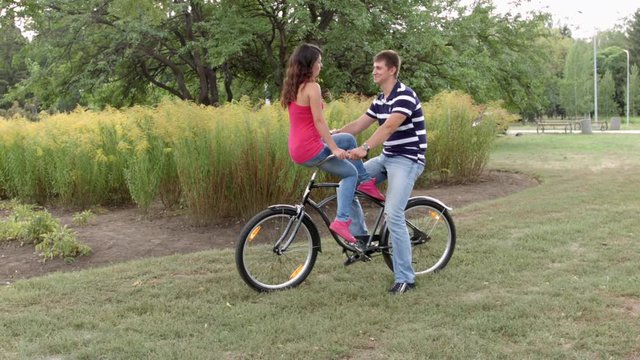 HD A couple is sitting on one bycile looking at each other and cahtting