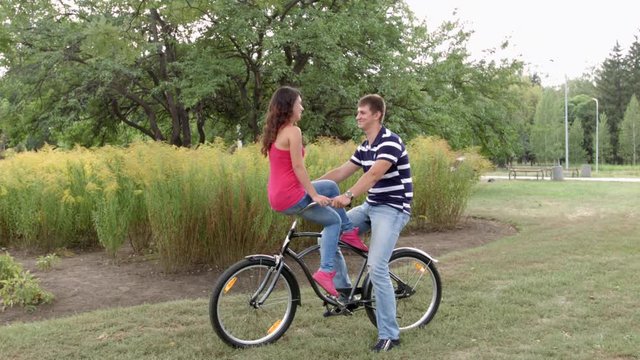 HD A happy couple is sitting on one bycile looking at each other and cahtting