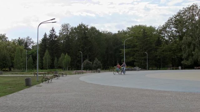 HD A Couple riding bicycles in the park, on block stones