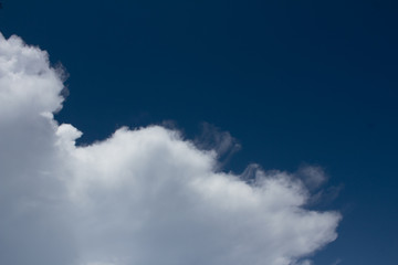 Fototapeta na wymiar white cumulus clouds fly on dark blue sky