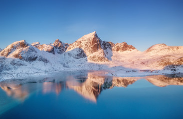 Aerial view at the mountains and reflection on the water surface. Lofoten islands, Norway. Natural landscape during sunrise from air. Drone landscape