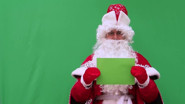 Father Frost holds the form. The New Year's character holds the A4 format model. Green background. An opportunity to insert the design.