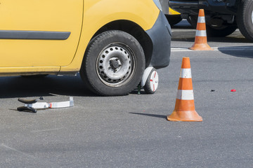 Close-up of a scooter on a pedestrian crossing. Issue of child safety on the road. Broken scooter under the wheels of the car