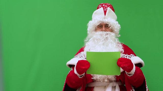 Father Frost holds the form. The New Year's character holds the A4 format model. Green background. An opportunity to insert the design.