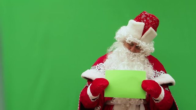 Father Frost holds the form. The New Year's character holds the A4 format model. Green background. An opportunity to insert the design.