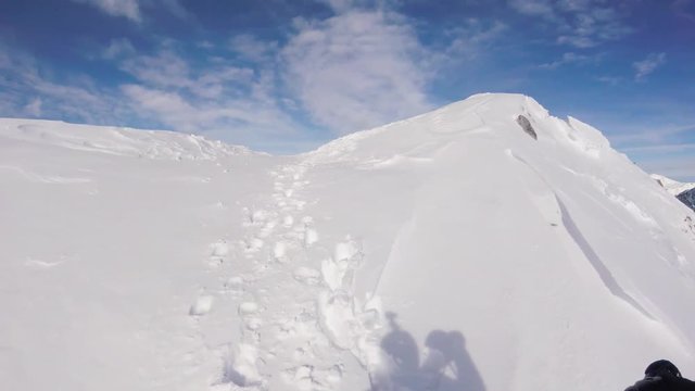 A skier with an action camera on his helmet climbing the snowy mountain