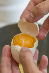 Female hands separate the egg white from the yolk over a bowl in the kitchen. the cook separates the yolk in the egg. vertical photo