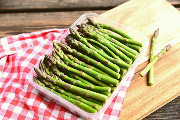 A lot of fresh Green Asparagus (genus) in plastic box on wooden floor..Spring vegetable season.