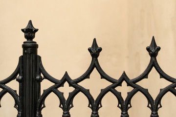Naklejka premium black metal forged fence on the background of a beige wall