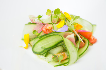 a portion of fresh cucumber salad with yogurt and dill flavouring decorated by cucumber flower.