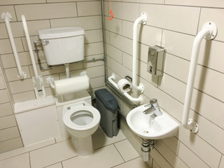 Disabled assisted bathroom toilet neutral tiles and white grab rails