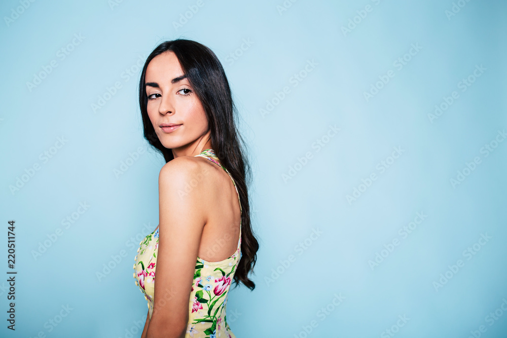 Wall mural close up portrait of lovely brunette woman in dress over blue background