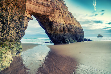 beautiful ocean landscape, the coast of Portugal, the Algarve, rocks on the sandy beach at sunset, a popular destination for travel in Europe
