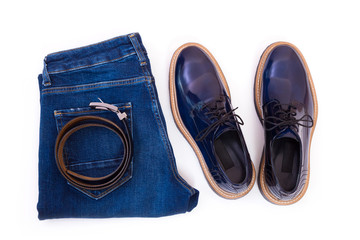 Men's jeans, leather belt and a pair of blue glossy shoes isolated on white background