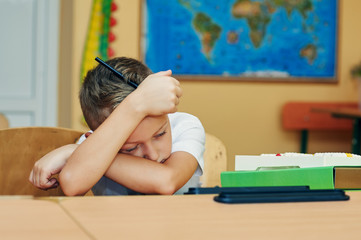 Tired elementary school kid in class .Pensive and tired boy in elementary school class