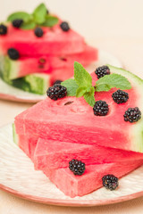 Watermelon slice pie with blackberries and mint leaf on pastel yellow background.