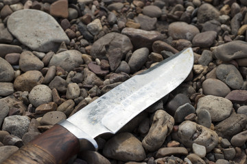 Hunting knife close-up, located on rocks in the summer