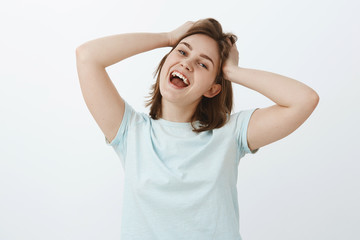 Woman going shopping feeling excited and pleased finally receiving paycheck. Portrait of carefree joyful attractive girl touching and messing up hair smiling broadly from positive emotions