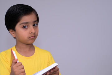 Young child holding book. With serious expression kid holding book looking at camera.