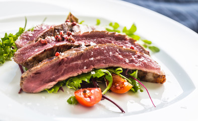 Close-up  juicy flank steak from vegetable salad.