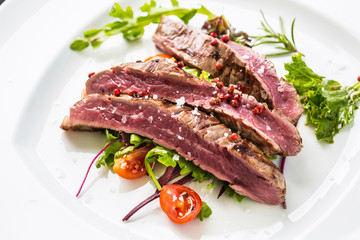 Close-up  juicy flank steak from vegetable salad.