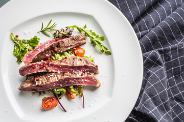 Close-up  juicy flank steak from vegetable salad.