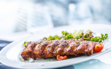Grilled barbecue pork ribs in a white plate as menu in pub.