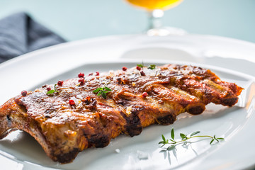Grilled barbecue pork ribs in a white plate as menu in pub.