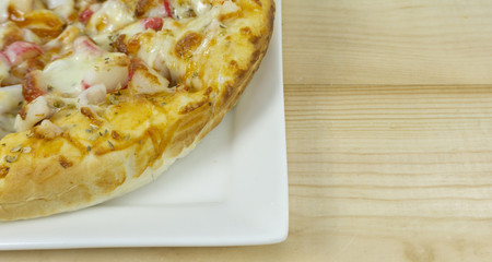Pizza seafood mozzarella cheese in white plate on wooden floor,Close up,copy space.