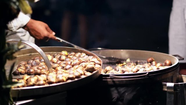 Italian street fast food. A street vendor sells roasted chestnut in night time . Baked chestnut at sale. 4K (UHD).