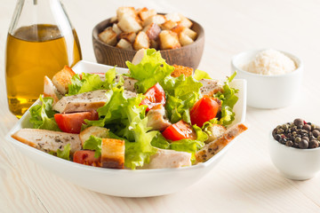 Fresh Greek salad with delicious  ruccola, spinach, cabbage, arugula, feta cheese, red onion and cherry tomato on wooden background. Oil, salt and pepper. Healthy and diet food concept.