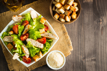 Fresh Greek salad with delicious  ruccola, spinach, cabbage, arugula, feta cheese, red onion and cherry tomato on wooden background. Oil, salt and pepper. Healthy and diet food concept.