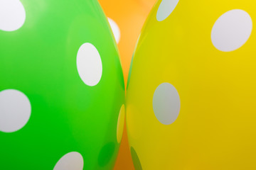 Background of green. orange and yellow balloons with the white circles on them. The optimistic picture, the symbol of happiness and joy