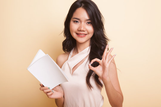 Young Asian woman show OK with a book.